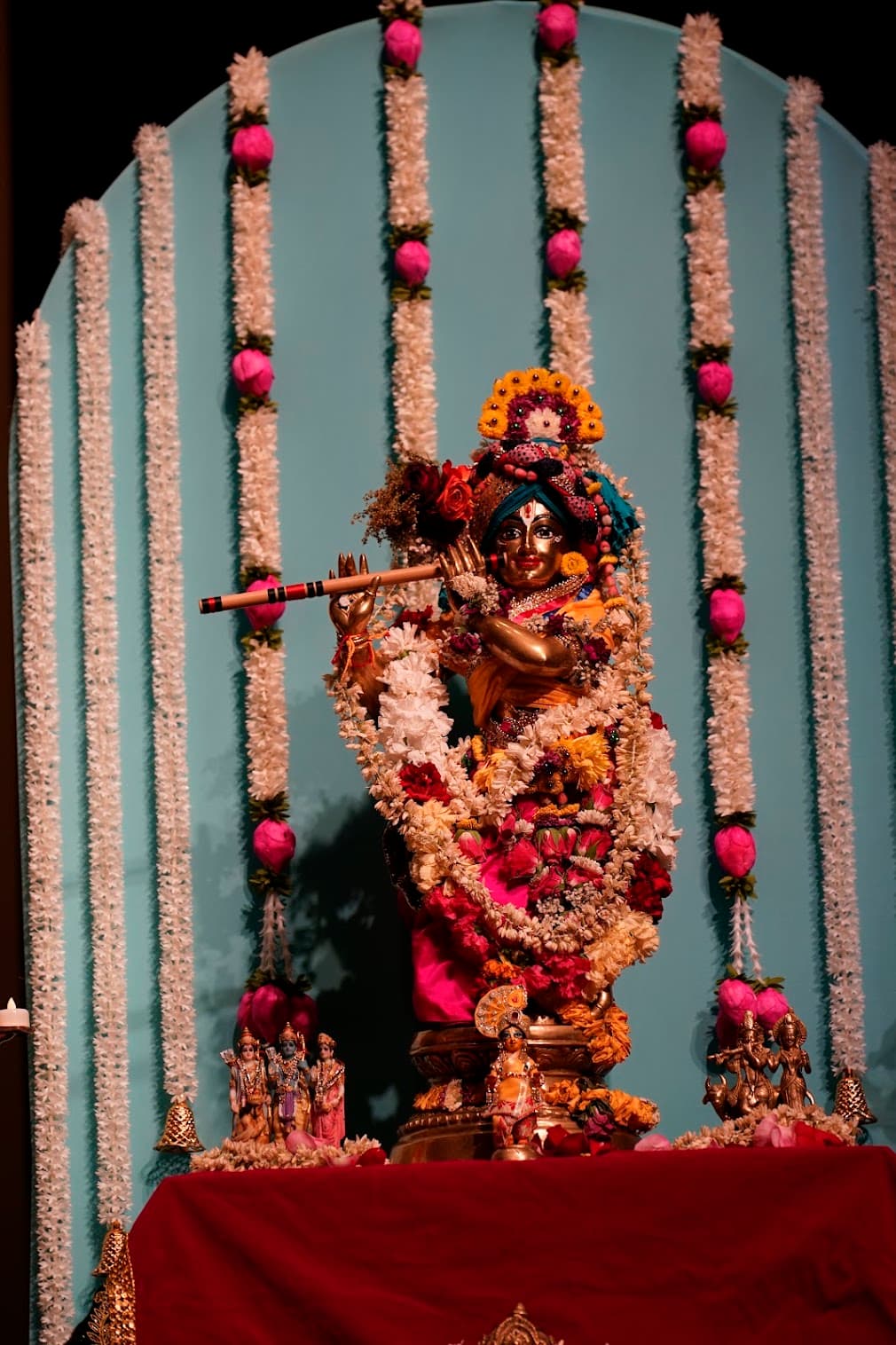 A garlanded brass murti beneath a turquoise arch installation